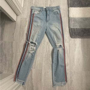 Blue jeans with rips and rainbow strip down the side